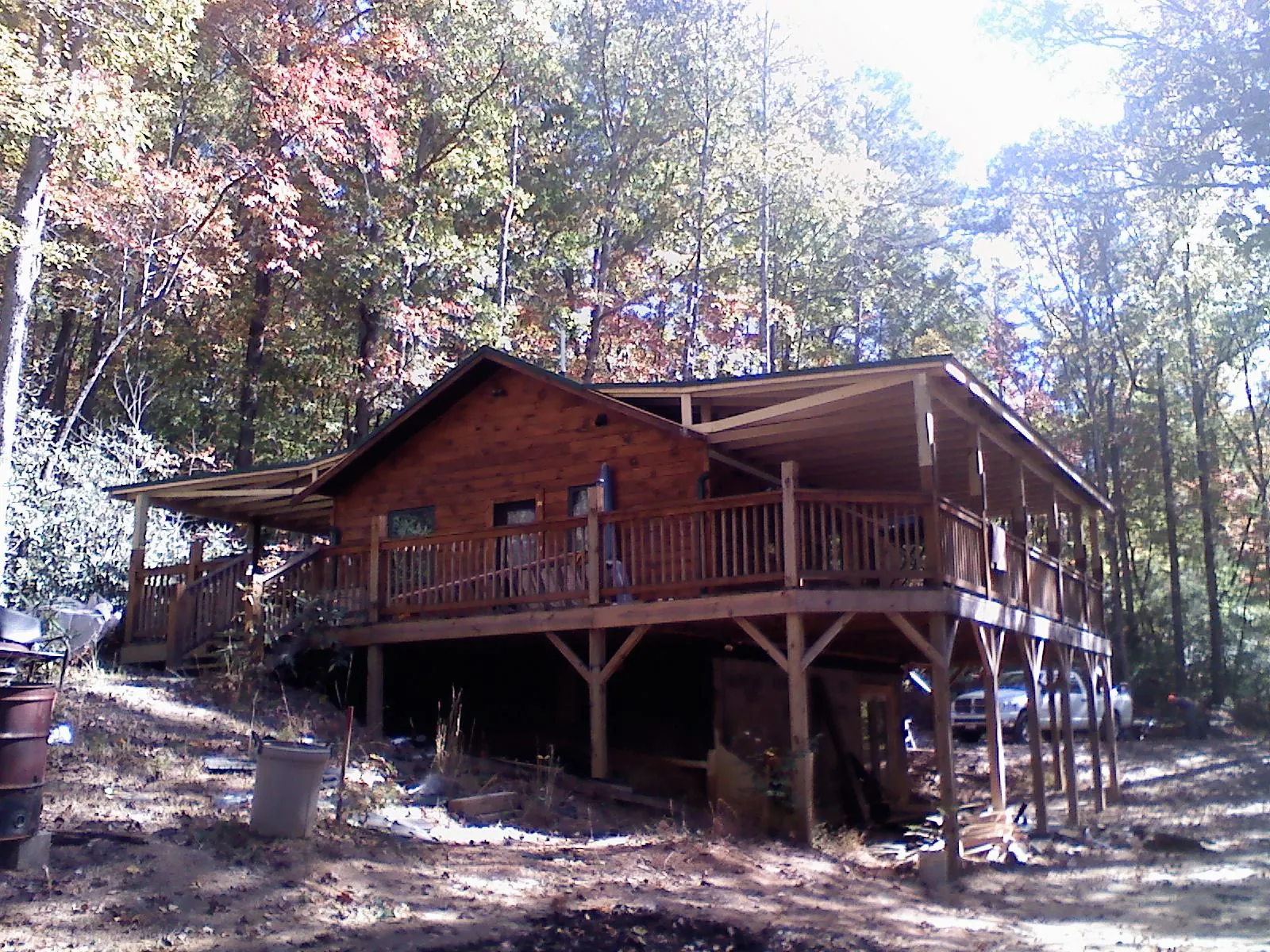 Log cabin with a wraparound porch and metal roof in the fall in Bedford